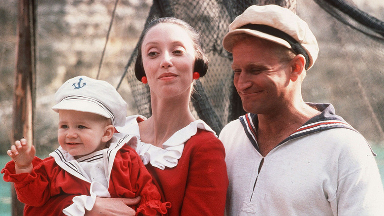 Robin Williams as Popeye smiling as Shelley Duvall as Olive Oyl cradles Swee'Pea baby in Popeye