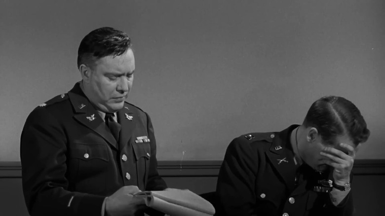 Major Moulton holding a book next to a crying Captain Hall in The Rack