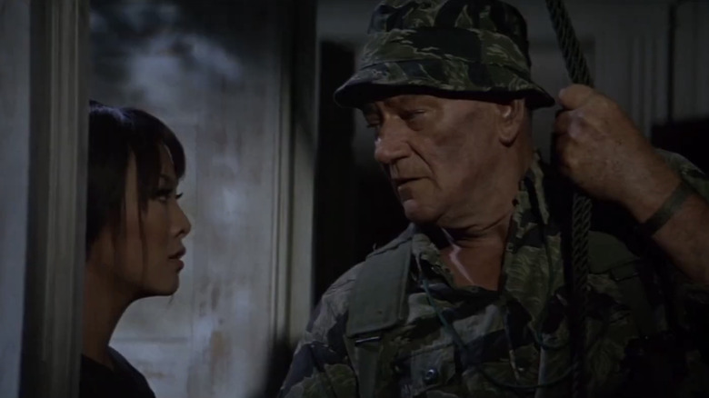 జాన్ వేన్ యొక్క కల్నల్ మైక్ కిర్బీ ది గ్రీన్ బెరెట్స్‌లో ఐరీన్ త్సు యొక్క లిన్ పక్కన నిలబడి ఉన్నాడు