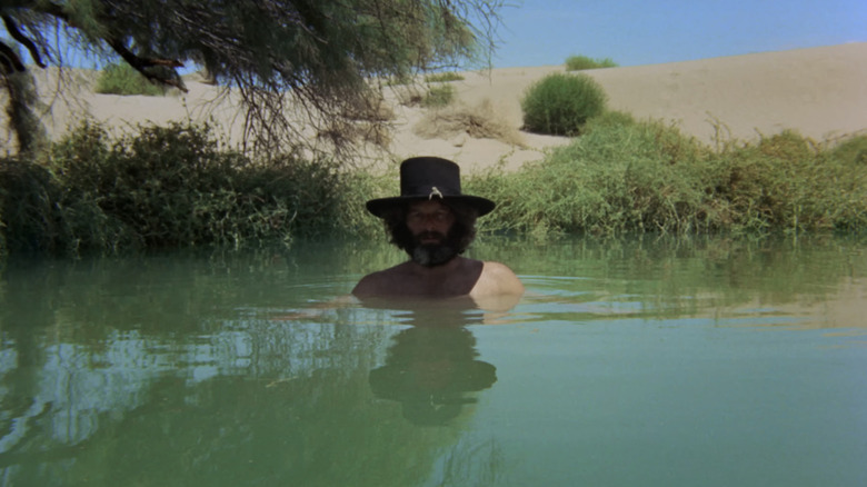 Alejandro Jodorowsky as El Topo stands with his head emerging from a pool of water in El Topo