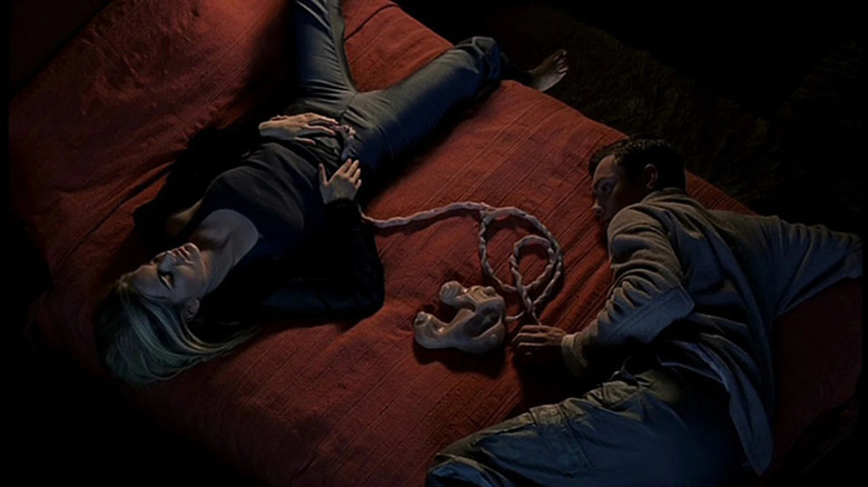 Allegra Gellar laying on a bed with Ted Pikul hooked up to a living pod in eXistenZ