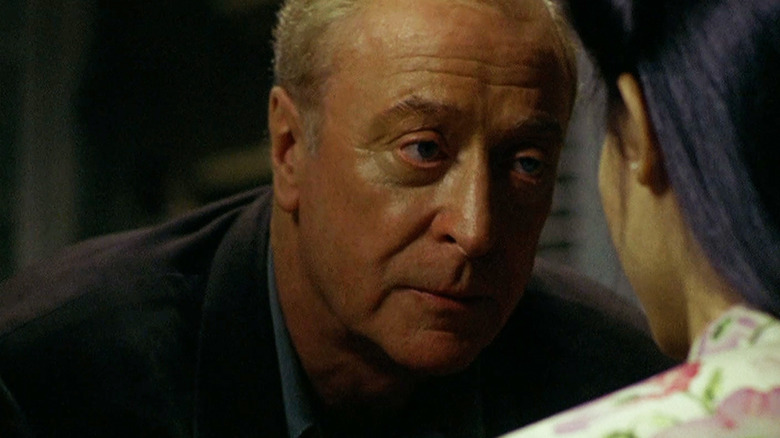 Thomas Fowler van Michael Caine leunt naar voren terwijl hij praat met Phuong van Do Thi Hai Yen in The Quiet American