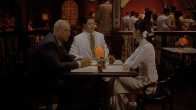 Thomas Fowler van Michael Caine, Alden Pyle van Brendan Fraser en Phuong van Do Thi Hai Yen zitten rond een tafel in een restaurant in The Quiet American