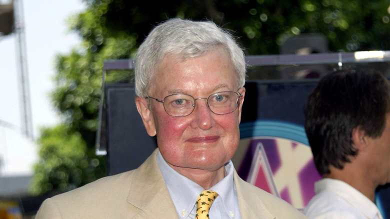 Roger Ebert smiles as he stands outside at an event