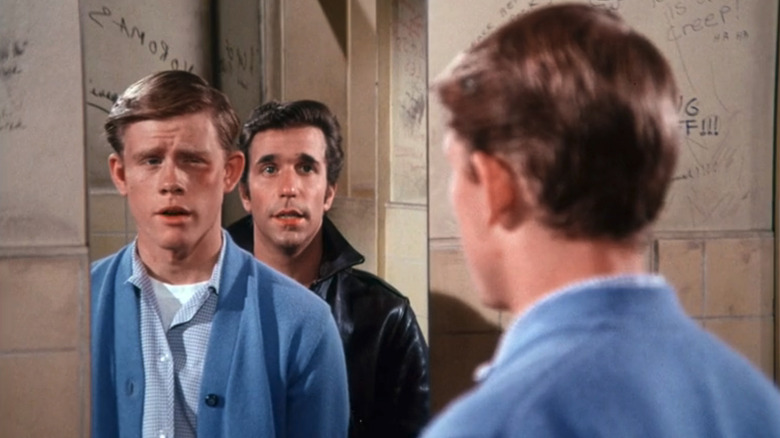 Henry Winkler's Arthur Fonzarelli stands behind Ron Howard's Richie Cunningham as he looks in a mirror in Happy Days