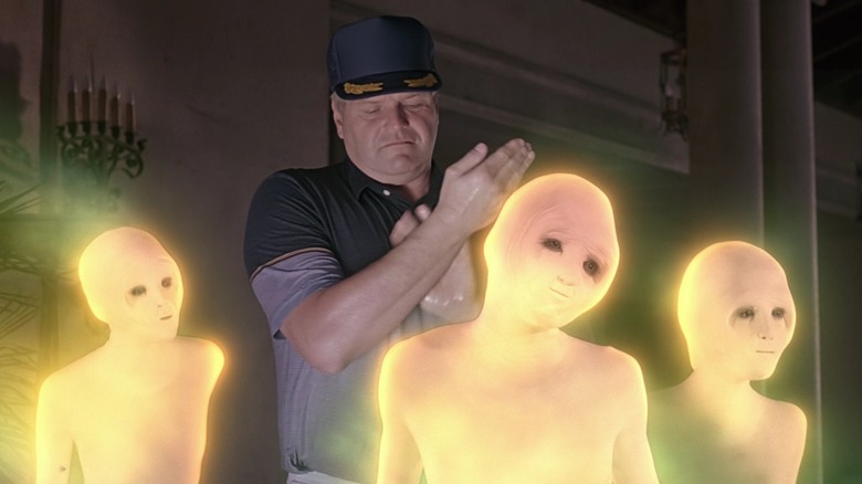 Walter, in a hat, rubbing his arm and surrounded by three glowing naked aliens from Cocoon
