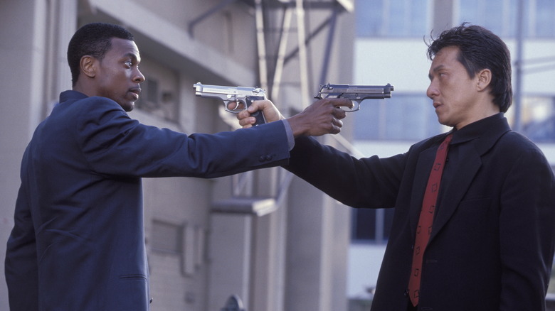 Jackie Chan como o inspetor-chefe Lee e Chris Tucker como o detetive James Carter apontando armas um para o outro na hora do rush