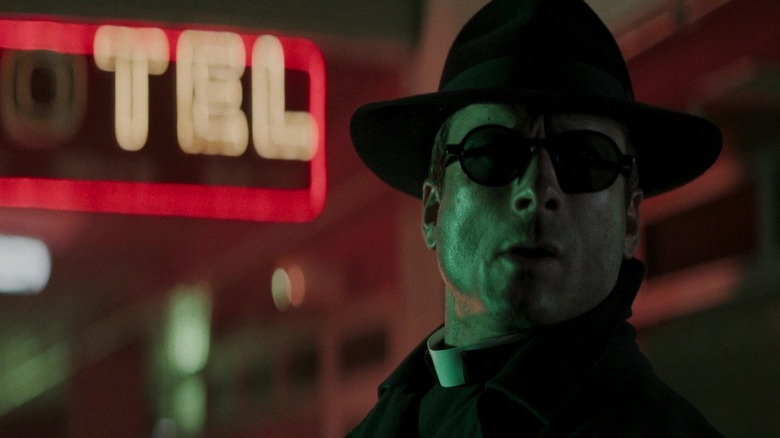 Glen Powell's Ben Richards looks off to his left while wearing a hat and glasses in The Running Man