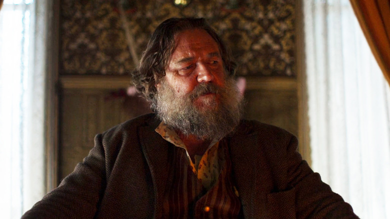 Russell Crowe as Harry Power sits at a table in True History of the Kelly Gang