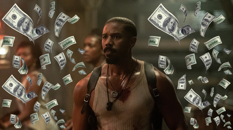 Michael B Jordan as Smoke standing inside the juke surrounded by money in Sinners