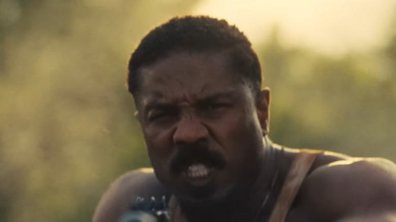 Michael B. Jordan as Smoke firing his tommy gun in Sinners