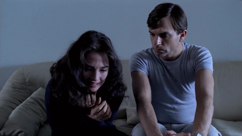 Sam Neill as Mark trails sits on the couch with Isabelle Adjani as Anna in Possession