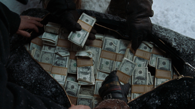 A bunch of hands opening a bag full of money in A Simple Plan