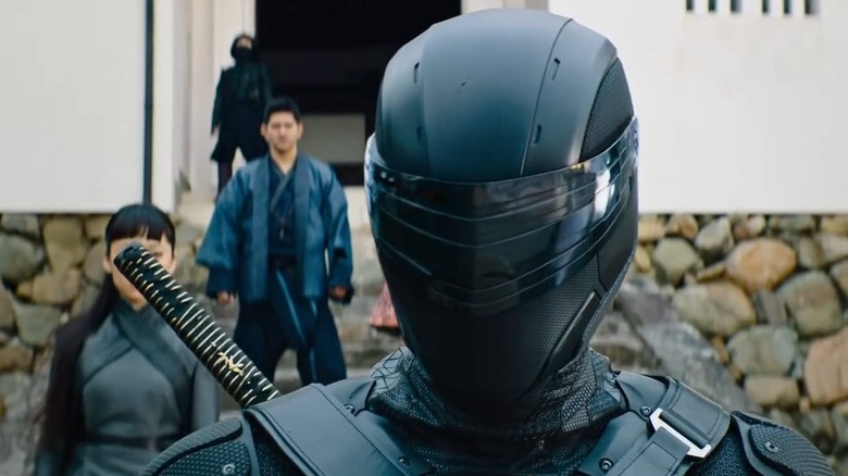 Henry Golding as Snake Eyes with his visor down in his costume in Snake Eyes: G.I. Joe Origins
