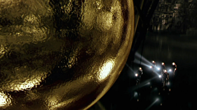 Un groupe de personnes munies de lampes de poche s'approchent de la sphère dans Sphere