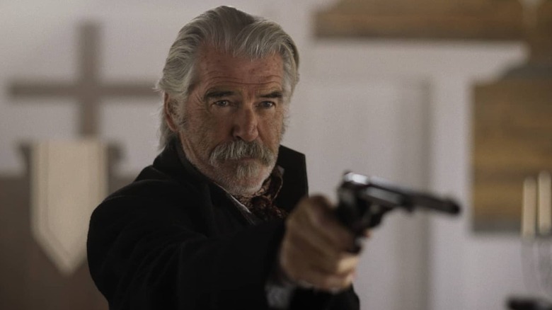 Pierce Brosnan as Gabriel Dove holding out his pistol in The Unholy Trinity
