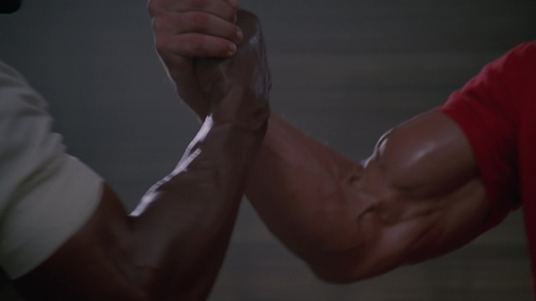 Two beefy arms grasping in a handshake in Predator