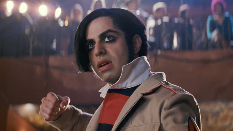 Satya Bhabha as Matthew Patel looking up with his fist raised to fight below a balcony of people in Scott Pilgrim vs. The World