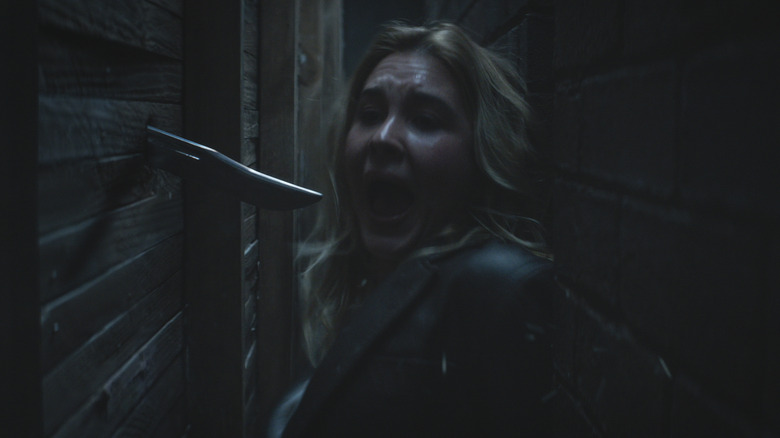 Isabel May as Tatum Evans sneaking through a crawlspace and screaming as a knife plunges through a wall in Scream 7