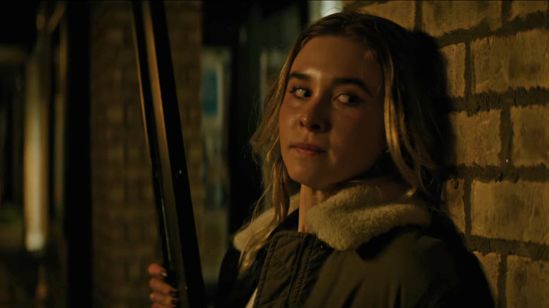 Tatum holding a gun and leaning on a wall in Scream 7