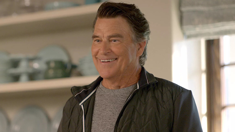 Ted McGinley as Derek on Shrinking, smiling in his kitchen