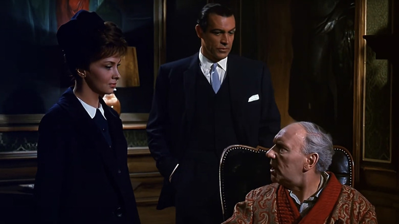 Sean Connery's Anthony Richmond stands behind Gina Lollobrigida's Maria Marcello as she speaks to Ralph Richardson's Charles Richmond in Woman of Straw