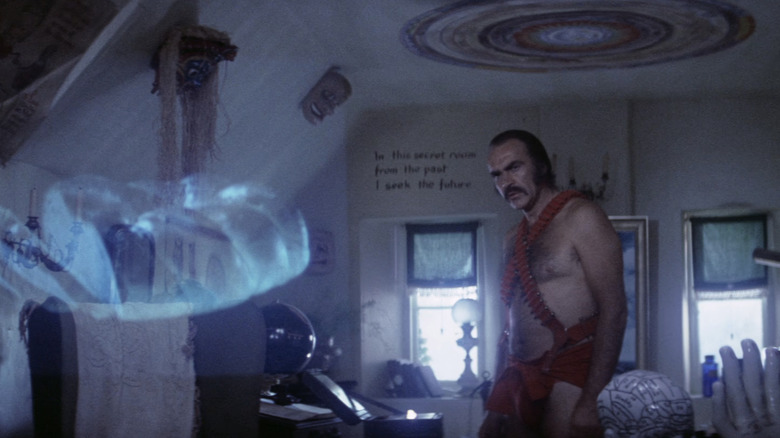 Sean Connery's Zed stands in a room with a hologram in Zardoz