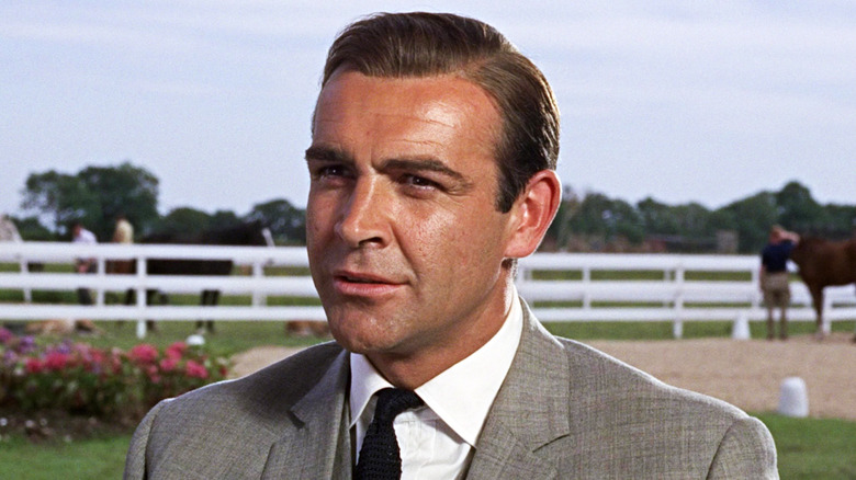 Sean Connery's James Bond sits outside in a suit in Goldfinger