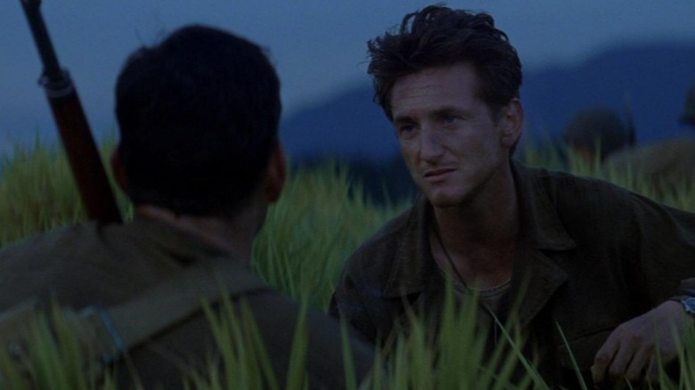 Sean Penn crouches in field