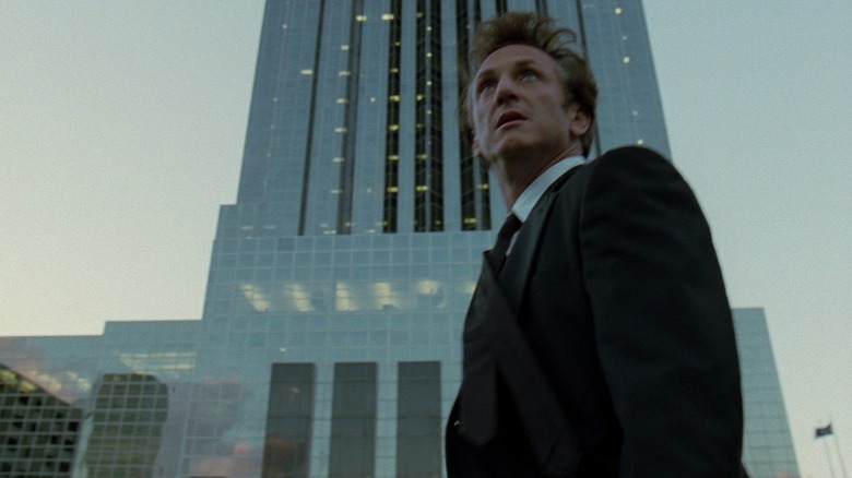 Sean Penn stands next to tall building