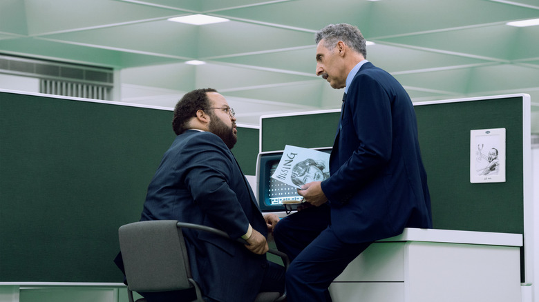 Zach Cherry and John Turturro as Dylan G. and Irving B., respectively, sit at a table in a scene from Season 2 of the series 