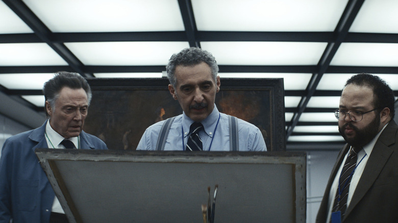 Christopher Walken como Burt G., John Turturro como Irving B. e Zach Cherry como Dylan G. olhando para uma pintura misteriosa na Severance temporada 1