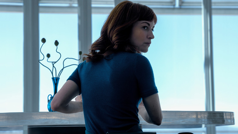 Helena sitting down and looking over her shoulder on Severance