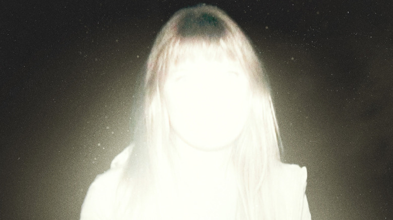 Sarah Durn as Riley distorted by light in the darkness on the poster for Shelby Oaks