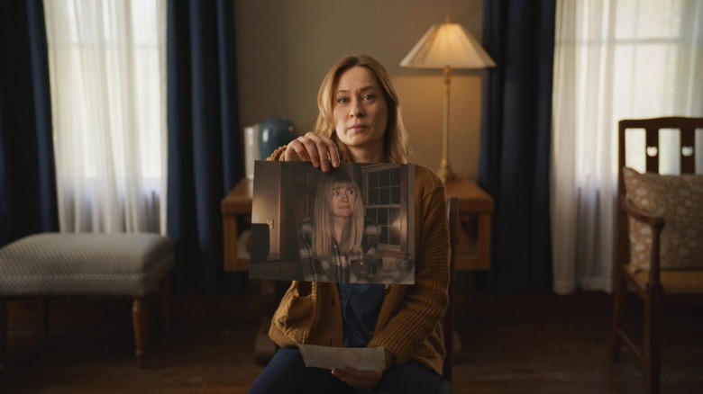 Camille Sullivan as Mia holding up a picture of Riley in Shelby Oaks