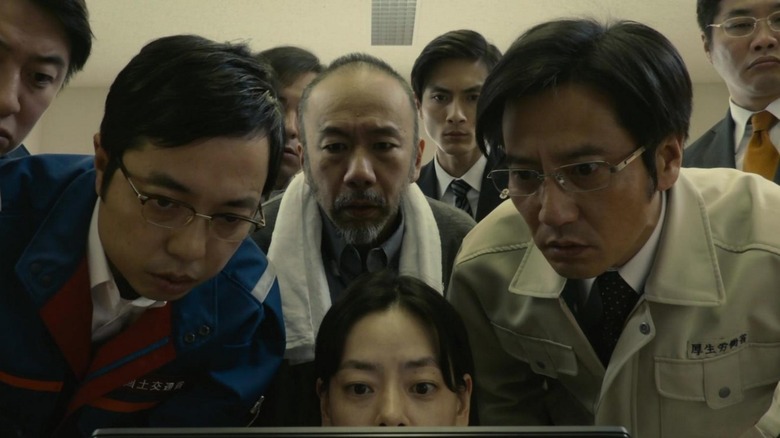 Shin Godzilla research team crowds around laptop