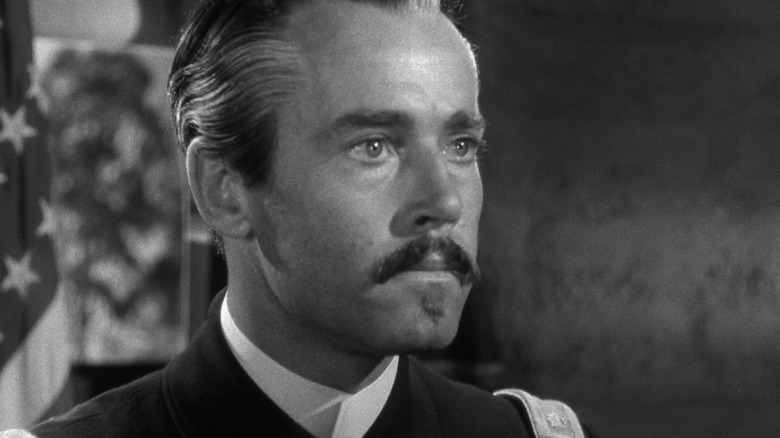 Owen Thursday, with a mustache and slick hair, looking intent in Fort Apache