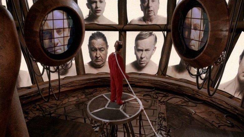A prisoner sees a wall of faces on various screens