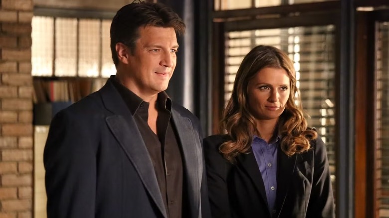 Richard Castle (Nathan Fillion) and Kate Beckett (Stana Katic) stand smiling next to each other in Castle