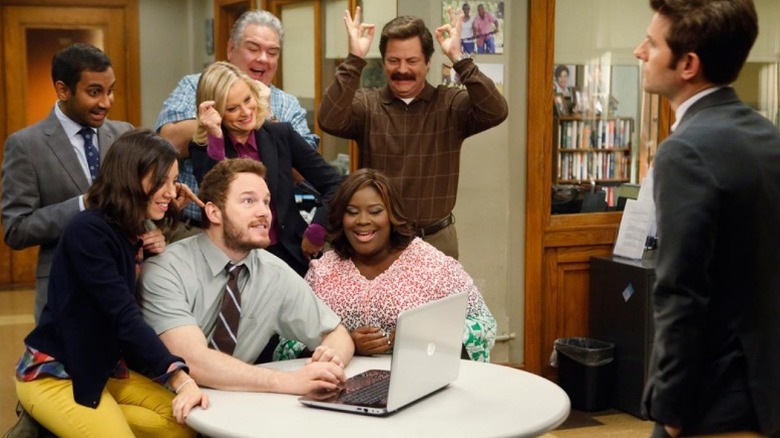 The cast of Parks & Recreation celebrates around a laptop computer