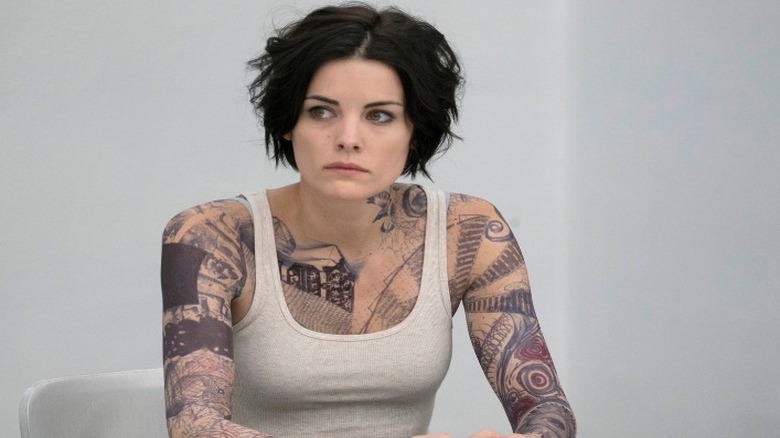 Jamie Alexander sits in chair tattoos blindspot