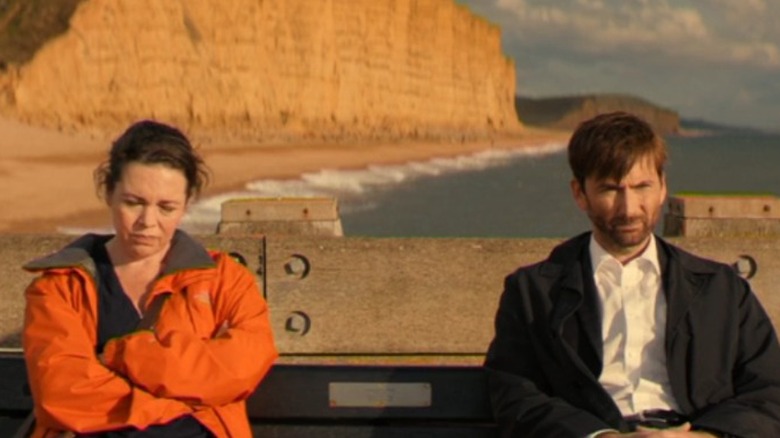 Olivia Coleman and David Tennant sitting by oceanside cliffs
