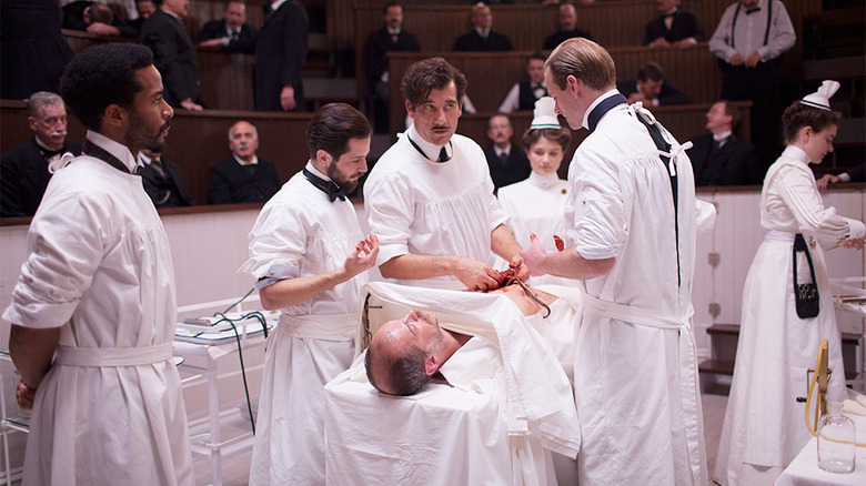 Team of surgeons conduct surgery in old-fashioned operating theater