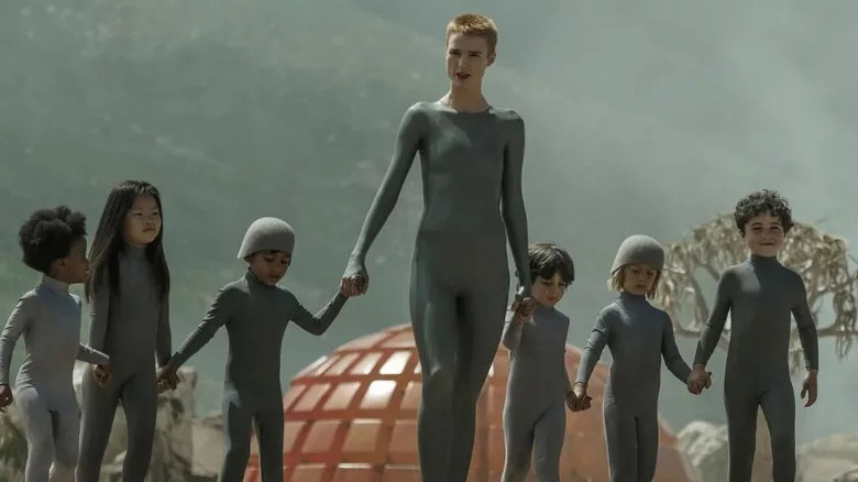 Raised By Wolves' Amanda Collin in grey holding hands with children