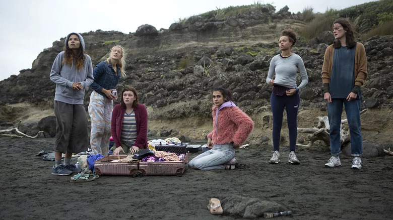 The Wilds' girls sitting and standing on a beach