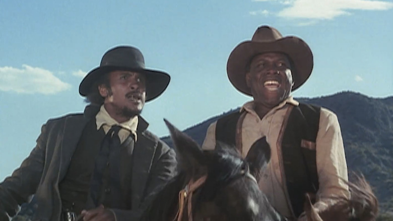 Harry Belafonte's Preacher sits on a horse next to Sidney Poitier's Buck in Buck and the Preacher