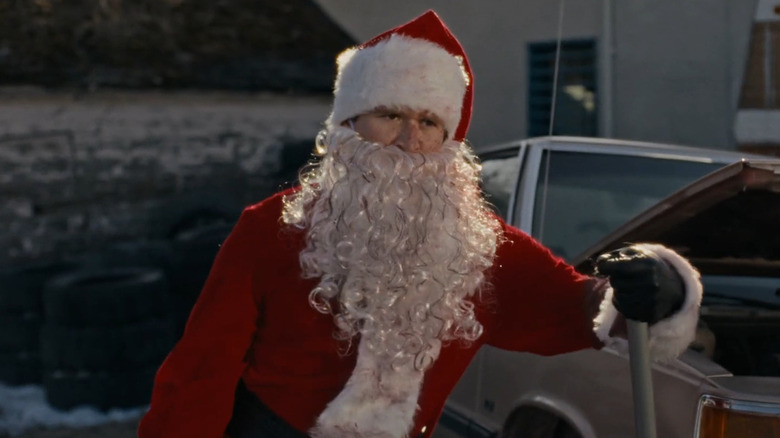Rohan Campbell as Billy in his Santa costume leaning on a car jack in Silent Night, Deadly Night (2025)