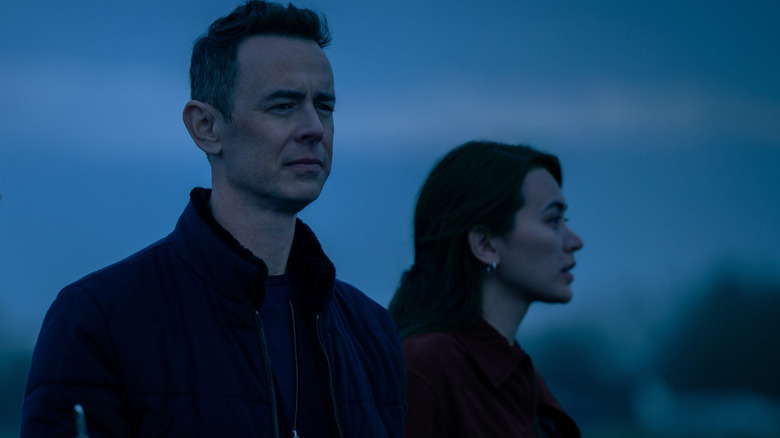 Colin Hanks as Per Stensen standing next to Jessica Henwick as Helen Drew in an open field in Silo