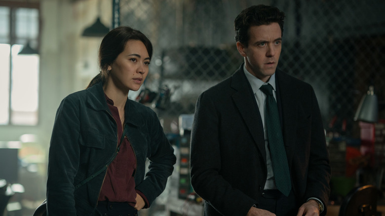 Jessica Henwick as Helen Drew standing next to Ashley Zukerman as Daniel Keene in a cluttered warehouse in Silo