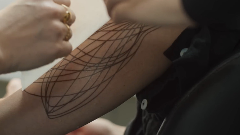 A makeup artist working on Juliette's tattoos from Silo